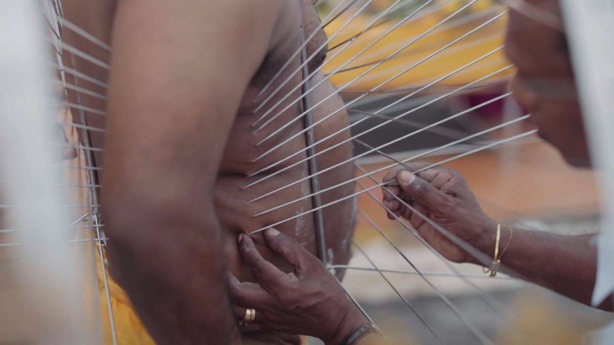 Through each arch of the frame, the piercers pull a thin skewer. The end of each disappears in the Kumar’s body - his torso and back.